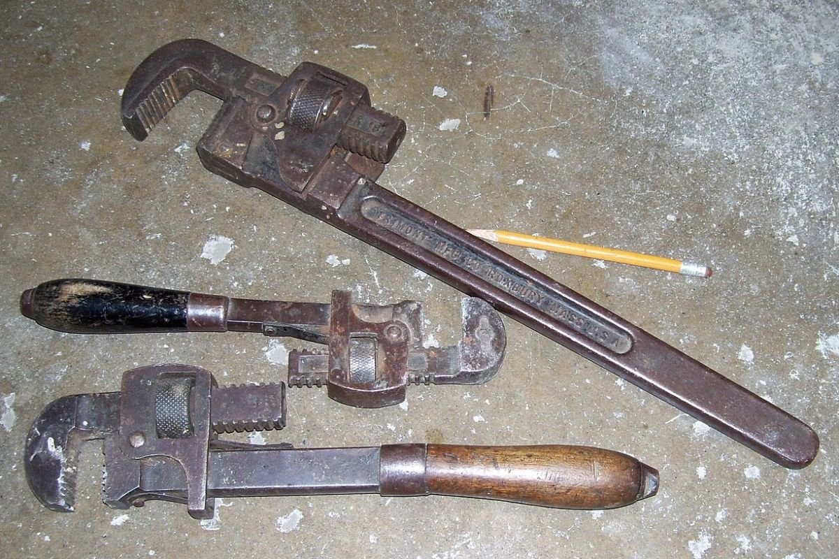 Three pipe wrenches of different sizes laid side by side for comparison