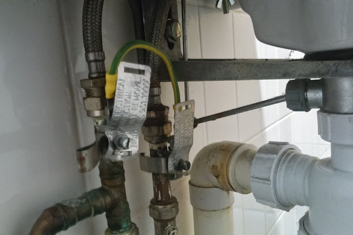 Shut-off valves, supply pipes and a drain trap under a bathroom sink
